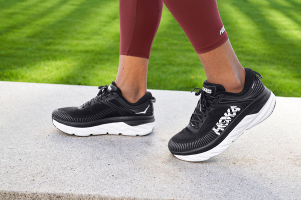 A woman running up stairs wearing HOKA Road shoes