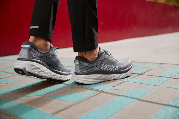 A woman running up stairs wearing HOKA Road shoes