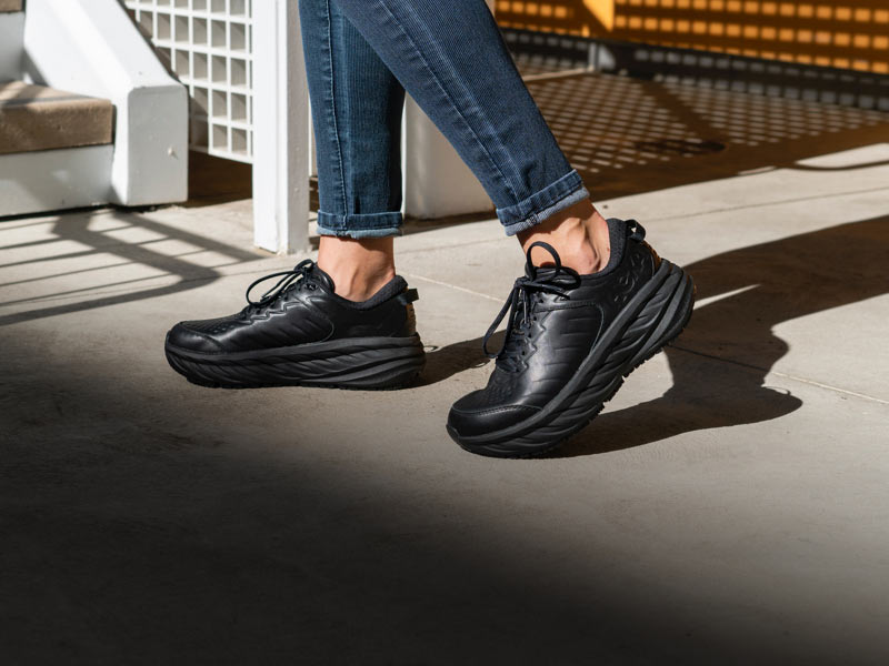 Woman walking in city, wearing HOKA shoes.